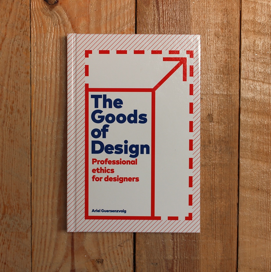 A book titled "The Goods of Design: Professional Ethics for Designers" by Ariel Guersenzvaig, with a white cover featuring bold blue and red text and a red dashed-line design, placed on a wooden surface.